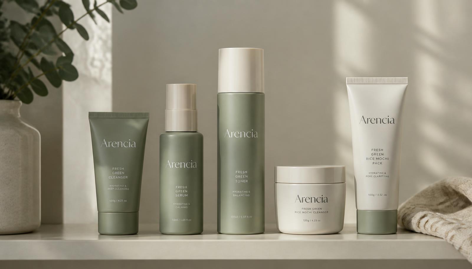 A row of sage-green and cream skincare bottles arranged on a bathroom shelf in soft natural light