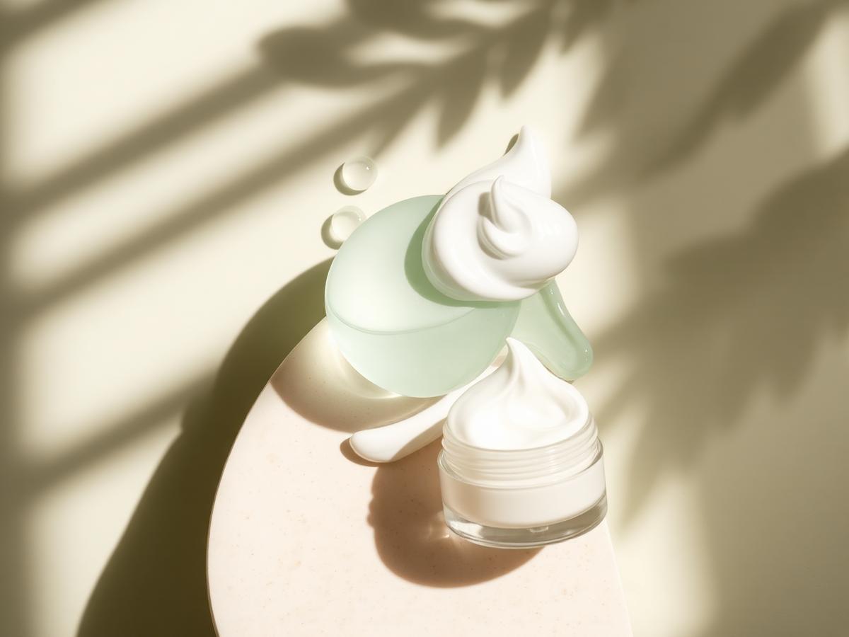 Skincare textures arranged from watery serum to thick cream on a pale stone surface